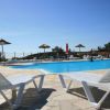 Piscina circondata da lettini e ombrelloni sotto il sole.