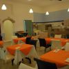 Un ristorante con tavoli apparecchiati e tovaglie arancioni.
