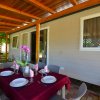 Veranda con tavolo apparecchiato e copertura in legno.