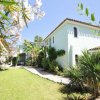 Casa azzurra con giardino e vegetazione.