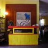 Reception con scrivania gialla e insegna blu su sfondo giallo.