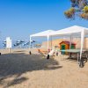 Area gioco sulla spiaggia con tenda bianca e casetta.