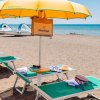 Spiaggia con ombrelloni gialli, lettini verdi e mare sullo sfondo.