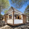 Una tenda di legno e tela tra alberi soleggiati.