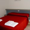 Letto matrimoniale con copriletto rosso acceso, due asciugamani piegati sui piedi del letto.