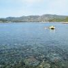 Mare limpido con una zattera e colline sullo sfondo.