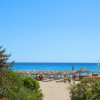 Spiaggia sabbiosa con mare azzurro e ombrelloni.