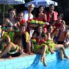 Un gruppo di persone in costumi colorati, seduti vicino a una piscina sotto ombrelloni.