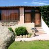 Casa con facciata in pietra, scale e giardino verde, cielo azzurro sopra.
