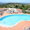Piscina a forma di fagiolo circondata da lettini e ombrelloni. Vista panoramica.