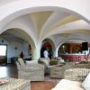 Salone con poltrone in vimini e soffitto ad arco, vista verso il bar.