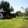 Un giardino con casetta da gioco, scivolo rosso e altalena.