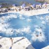 Una piscina affollata vicino al mare, con persone che si divertono in acqua.