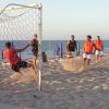 Partita di calcio sulla spiaggia, un giocatore calcia il pallone verso la porta.