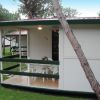 Veranda di una casa mobile con tavolo e sedie, circondata da alberi.