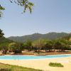 Piscina all'aperto circondata da alberi e colline sotto un cielo sereno.